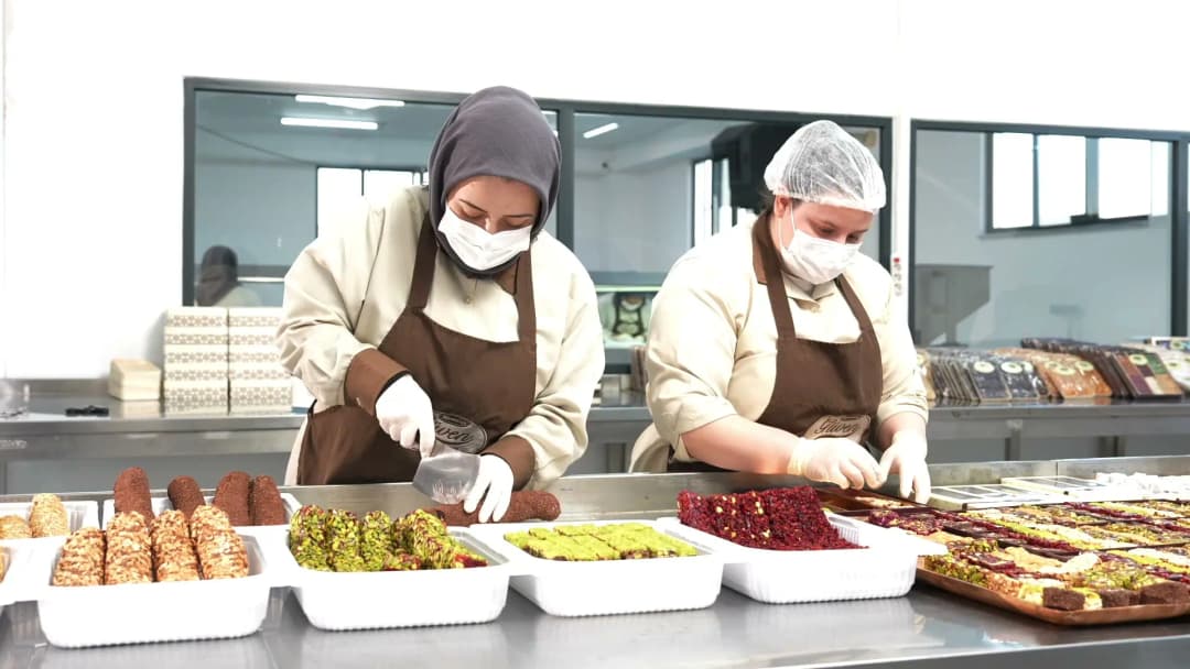 Arnavutköy tesisinde bone ve eldivenli çalışanlar lokum tepsilerini hazırlıyor